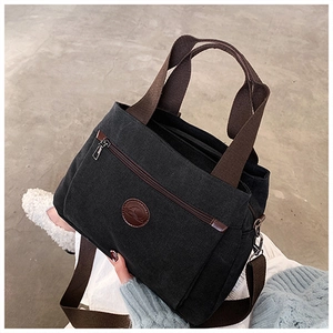 Dettaglio borsa tote in tela nera con manici intrecciati marroni e ganci in metallo resistenti