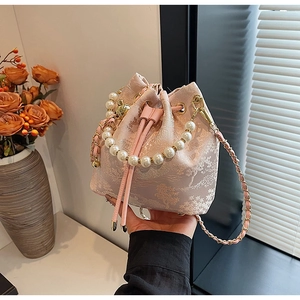 Detail of light pink bucket bag with floral jacquard, pearl handle and gold chain strap