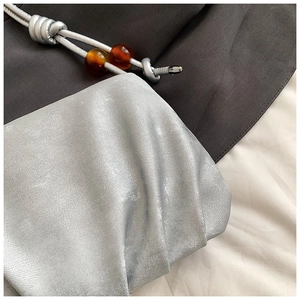 Detalle del bolso nube plisado plateado con acabado metálico y cuentas de ámbar