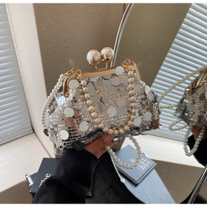 Detail of silver sequin clutch bag featuring pearl handle and decorative shell clasp