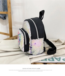 Dettaglio di paillettes iridescenti e ricamo a unicorno su uno zainetto in pelle nera