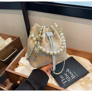 Detailed view of the gold jacquard pattern and elegant pearl handle on a blue bucket bag