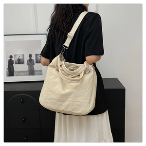 Détail d'un sac cabas beige montrant la texture plissée et la large bandoulière réglable