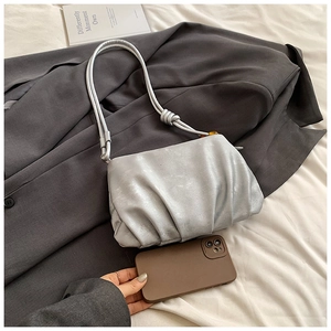 Bolso nube plisado plateado con perla de ámbar sobre traje gris y ropa de cama blanca pura