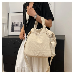 Détail d'un grand sac cabas crème avec bandoulière tissée et texture de tissu plissée