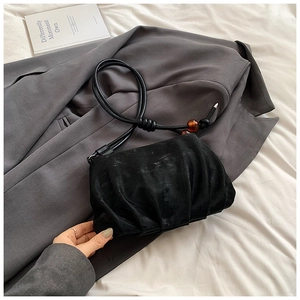 Detalle del bolso de ante plisado negro con elegantes cuentas de color ámbar