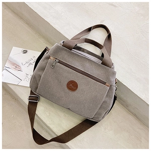 Dettaglio borsa tote in tela grigio scuro con tracolla marrone e cerniere in metallo argento