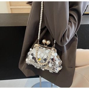 Detail of silver sequin clutch bag with pearl handle hanging on a grey blazer
