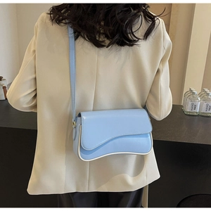 Achteraanzicht van model met een lichtblauwe crossbodytas met golvende flap en leren riem