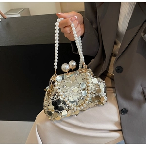 Detail of luxury sequined evening bag featuring a double pearl handle and metal clasp