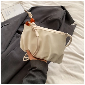 Detalle de bolso nube plisado crema con cuentas de ámbar y una correa con nudos