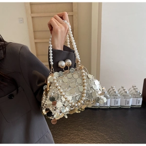 Close-up of champagne silver sequin evening bag with pearl handle and golden clasp