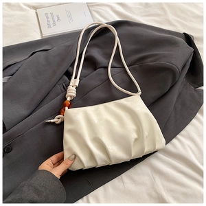 Detalle de bolso nube plisado blanco con cuentas de ámbar en la correa y suave textura PU