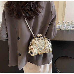 Close-up of a silver sequined evening clutch with pearl clasp and chain strap