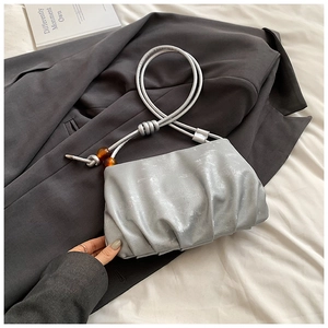 Detalle del bolso nube plisado plateado con cuentas de ámbar sobre traje gris