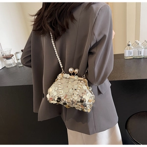 Detail of a gold sequin evening bag with large pearl clasp and pearl shoulder strap
