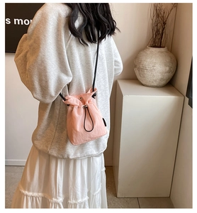 Detail of light pink drawstring mini bucket bag with sleek black shoulder strap and silver toggle