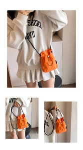 Detail view of bright orange nylon mini bucket bag with drawstring and thin black strap