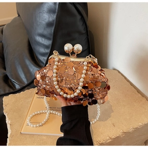 Macro detail of luxury evening bag with gold sequins, pearl clasp, and metal frame