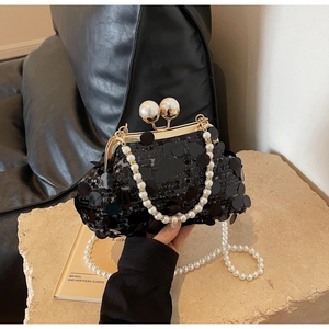 Detail of black sequin evening bag featuring gold frame and white pearl double clasps