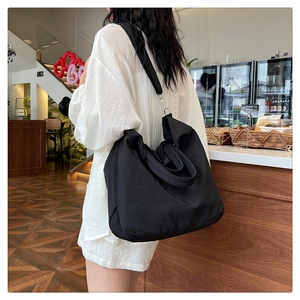 Détail du sac cabas en toile noire avec bandoulière réglable et boucle en métal robuste
