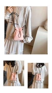 Detail of pink nylon mini bucket bag featuring black drawstring closure and crossbody strap