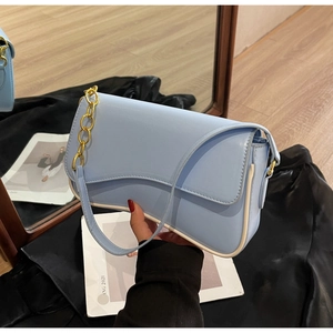 Gedetailleerd beeld van lichtblauwe lederen baguette tas met witte bies en gouden ketting