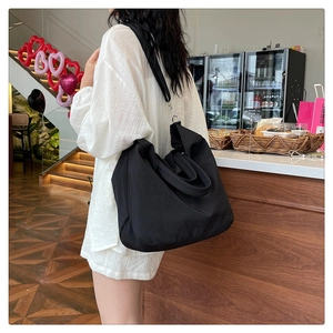Sac fourre-tout pratique en nylon noir porté en bandoulière dans un café moderne