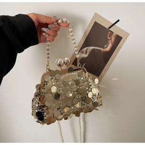 Detail view of a gold sequin evening clutch bag with pearl handle and metal clip closure