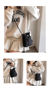 Detail of black nylon mini bucket bag with drawstring closure and silver metallic buckle