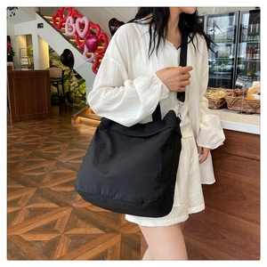 Gros plan détaillé d'un grand sac cabas en nylon noir avec deux sangles dans un café