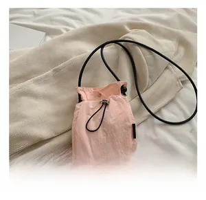 Detail of pink nylon drawstring mini bag with adjustable cord and slim black leather strap