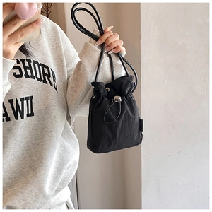 Detail view of a black drawstring bucket bag showing the nylon fabric and silver metal toggle