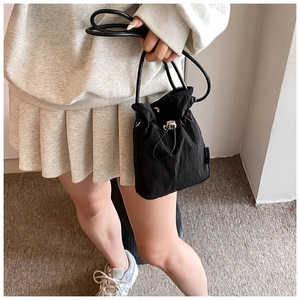 Detailed view of black nylon drawstring bucket bag with silver metal cord lock
