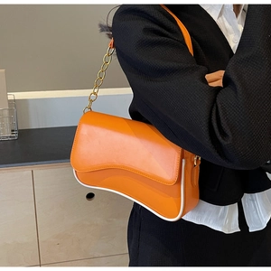 Detail van oranje schoudertas met gegolfde bodem, witte biezen en gouden kettingriem