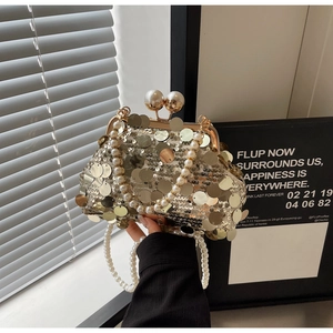 Detailed view of luxury gold sequin evening bag with large pearl clasp and handle