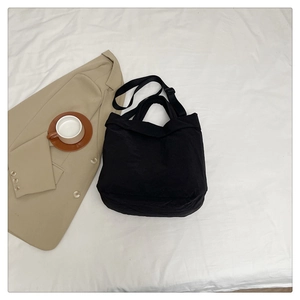 Vue détaillée d'un grand sac cabas noir minimaliste avec bandoulière réglable