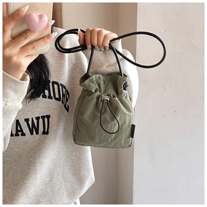 Detail of green mini drawstring bucket bag showing durable nylon ripstop texture and buckle