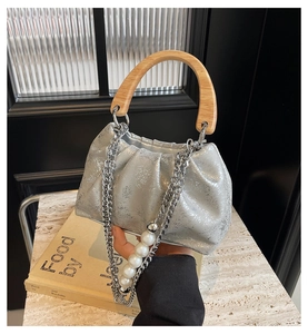 Détail du sac seau plissé argenté avec poignée en bois et chaîne à perles