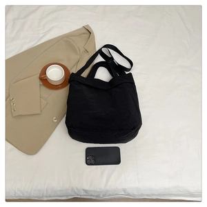 Détail du grand sac cabas en nylon noir souple avec larges anses et téléphone pour l'échelle