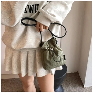 Detail of army green drawstring mini bucket bag in textured plaid nylon fabric