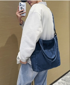 Dettaglio della borsa tote in denim blu scuro con cuciture a contrasto e tasche esterne