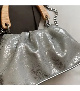 Détail du sac seau plissé argenté avec poignée en bois et bandoulière en chaîne