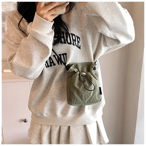 Close-up of olive green nylon drawstring crossbody bag shown on model for size and scale