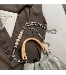 Détail du sac seau plissé argenté avec poignée en bois et bandoulière en perles