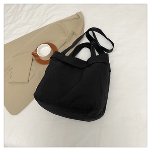 Vue à plat d'un grand sac de transport noir avec bandoulière sur un fond en tissu blanc