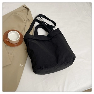 Détail du sac de banlieue en nylon noir avec bandoulière réglable sur fond de tissu blanc