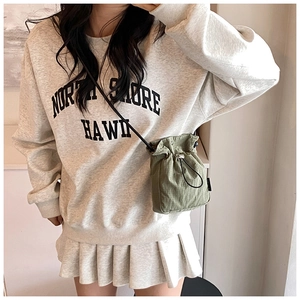 Detailed view of an olive green mini drawstring bucket bag worn with a casual outfit