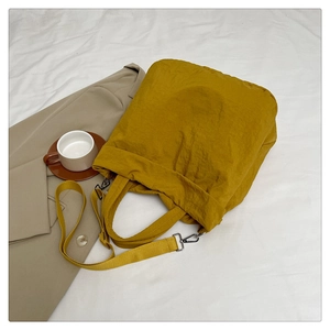 Détail du sac cabas jaune moutarde à texture froissée sur une parure de lit