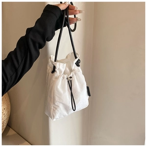 Detail of white nylon drawstring bag featuring delicate grid texture and slim black strap